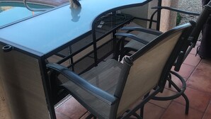 Eine Terrasse im Freien mit einem Tisch aus Glas und vier Stühlen.