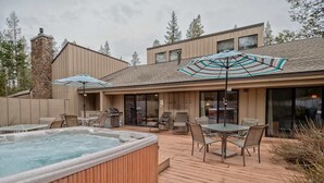 Une terrasse en bois avec un jacuzzi, des sièges d’extérieur et des parasols.