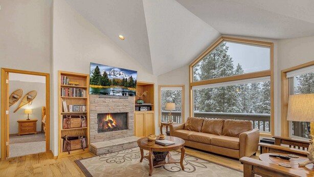 A spacious living room with a fireplace, large windows, a leather sofa, and a bookshelf. - AC, pet friendly, inside Sunriver, EV charger (Sunriver)