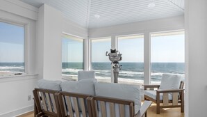 A room with a large window overlooking the ocean, a wooden bench, and a chair. - Perkins Cottage- Ocean Front/Pet Friendly Home (Atlantic Beach)