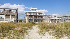 A beachfront property with a central building featuring a balcony and multiple windows. - Perkins Cottage- Ocean Front/Pet Friendly Home (Atlantic Beach)