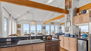 A spacious kitchen with a large island, wooden cabinets, and a view of the ocean. - Perkins Cottage- Ocean Front/Pet Friendly Home (Atlantic Beach)