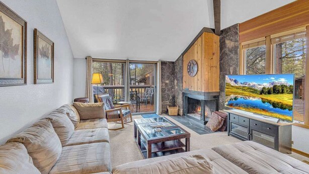 Amplia sala de estar con chimenea, televisor grande y zona de estar confortable.
