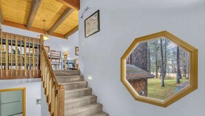 Una escalera con barandillas de madera y escalones alfombrados que conduce a una habitación con un amplio ventanal octogonal.