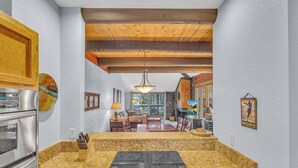 Una cocina con encimeras de granito, estufa integrada, armarios de madera y vista al área de comedor.
