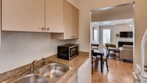 Una cucina con lavelli in acciaio inossidabile, un forno a microonde e un'area pranzo con tavolo e sedie.