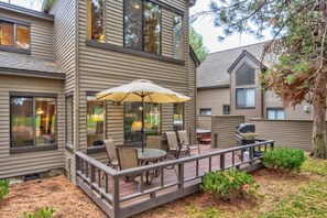 Une maison à deux étages dotée d’un patio couvert aménagé avec du mobilier d’extérieur et un barbecue.