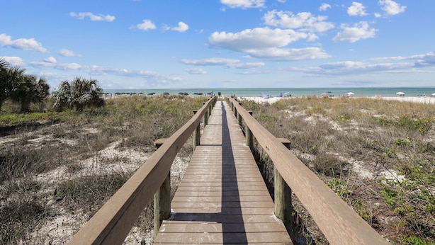 A wooden boardwalk leading to a beach with a clear sky and distant ocean view. - AJ's Bayside Treasure - Outstanding Waterfront Views & Private Beach Access! (Sarasota)