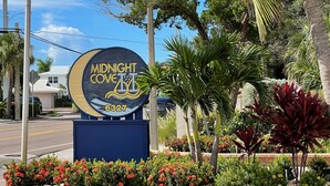A sign for 'Midnight Cove' with a beach scene and a phone number. - AJ's Bayside Treasure - Outstanding Waterfront Views & Private Beach Access! (Sarasota)