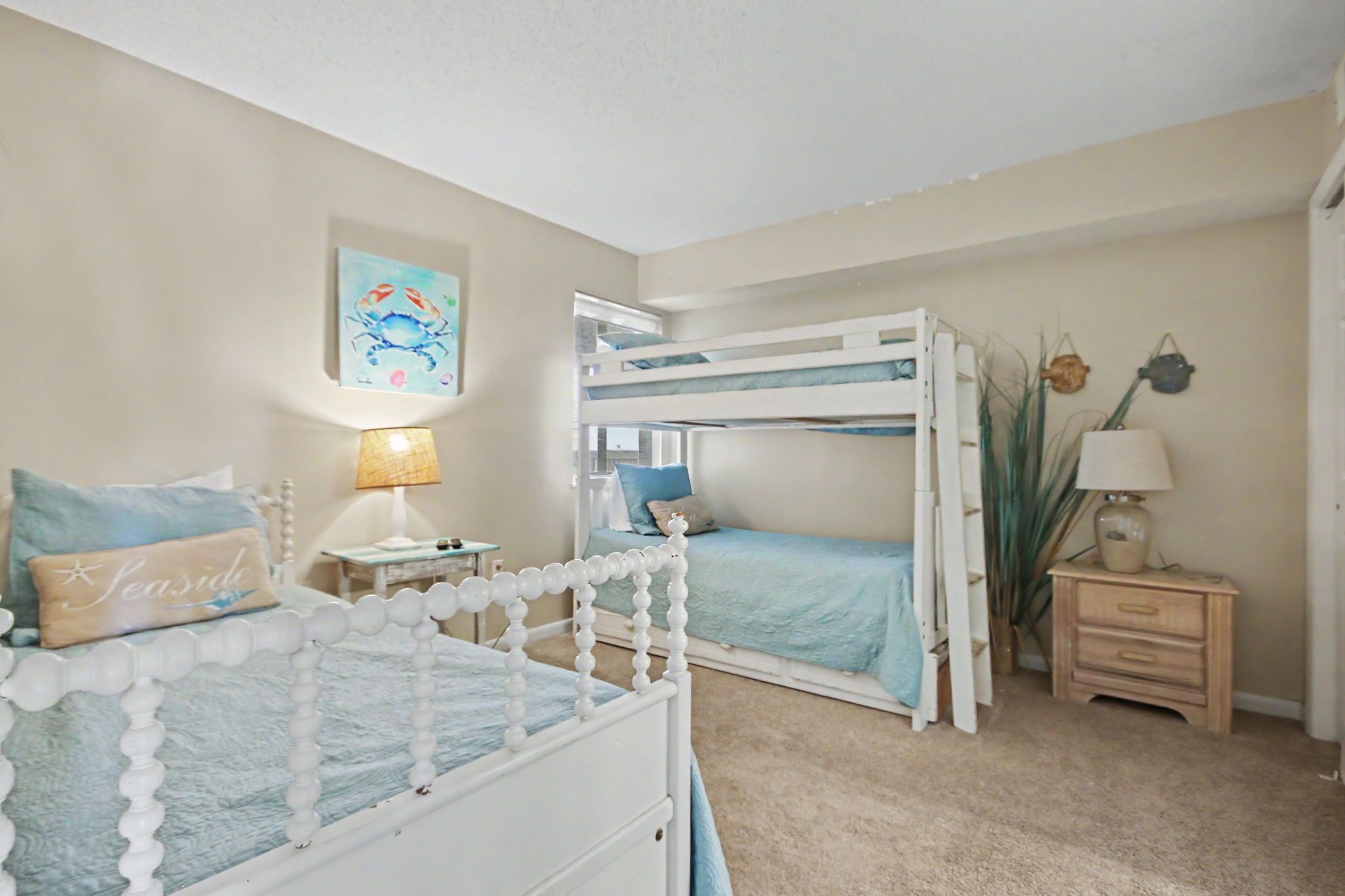A bedroom with a bunk bed, a bedside table with a lamp, a nightstand, and a wall-mounted shelf.