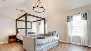 Tilava makuuhuone, jossa on nelipylväinen sänky, sohva ja yöpöytä.