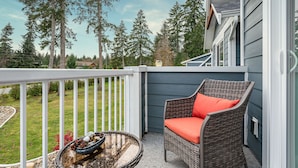 A balcony with a wicker chair and a fire pit.