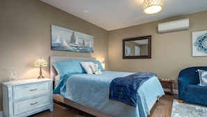 A bedroom with a bed, bedside table, lamp, and artwork on the wall.