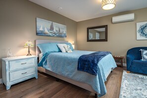 Quarto com cama, mesa de cabeceira, luminária e uma obra de arte na parede.
