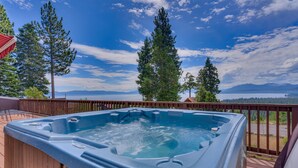 A hot tub on a wooden deck with a scenic view of mountains and trees.