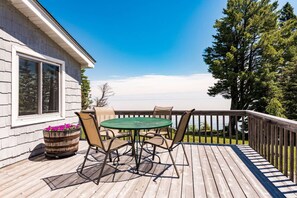 A wooden deck with a table and chairs, overlooking a body of water. - 4BR Lake Superior Private Beach (Knife River)