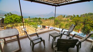 A balcony with a view of a mountainous landscape and a body of water. There are four chairs and a small table. - The Bob house (Mawal)