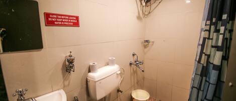 A small bathroom with a sink, toilet, and shower. There is a sign instructing to close the tap before leaving.