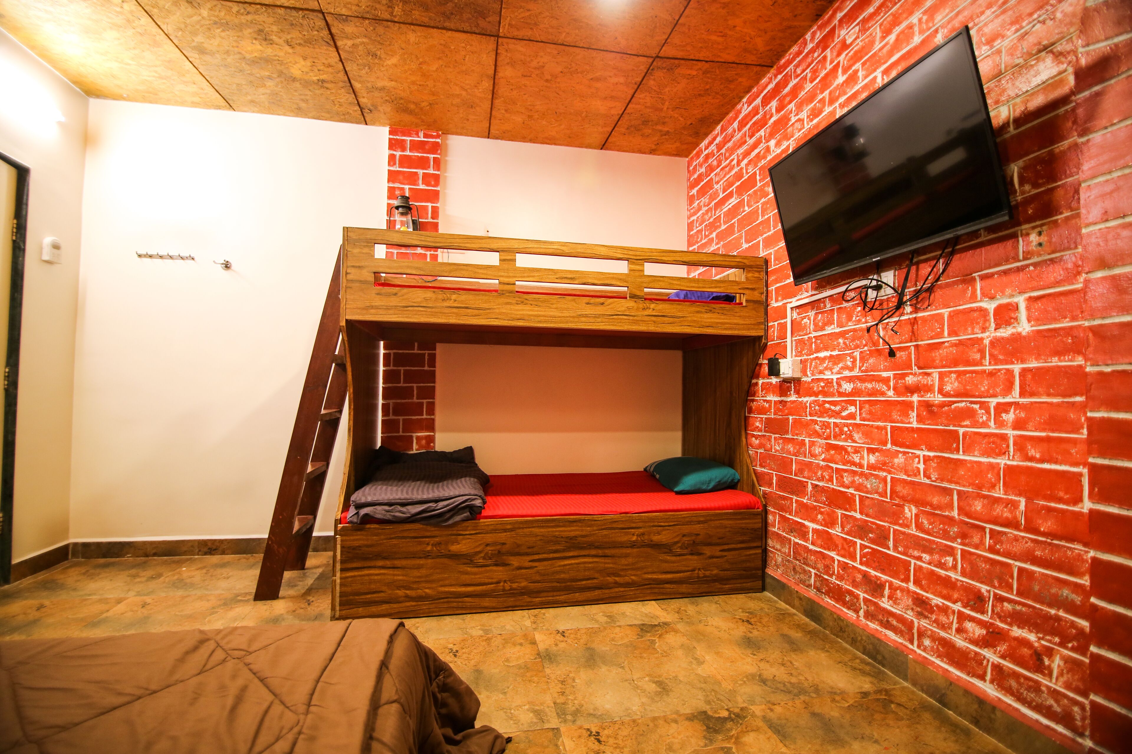 Habitación con literas, pared de ladrillo y televisor montado.
