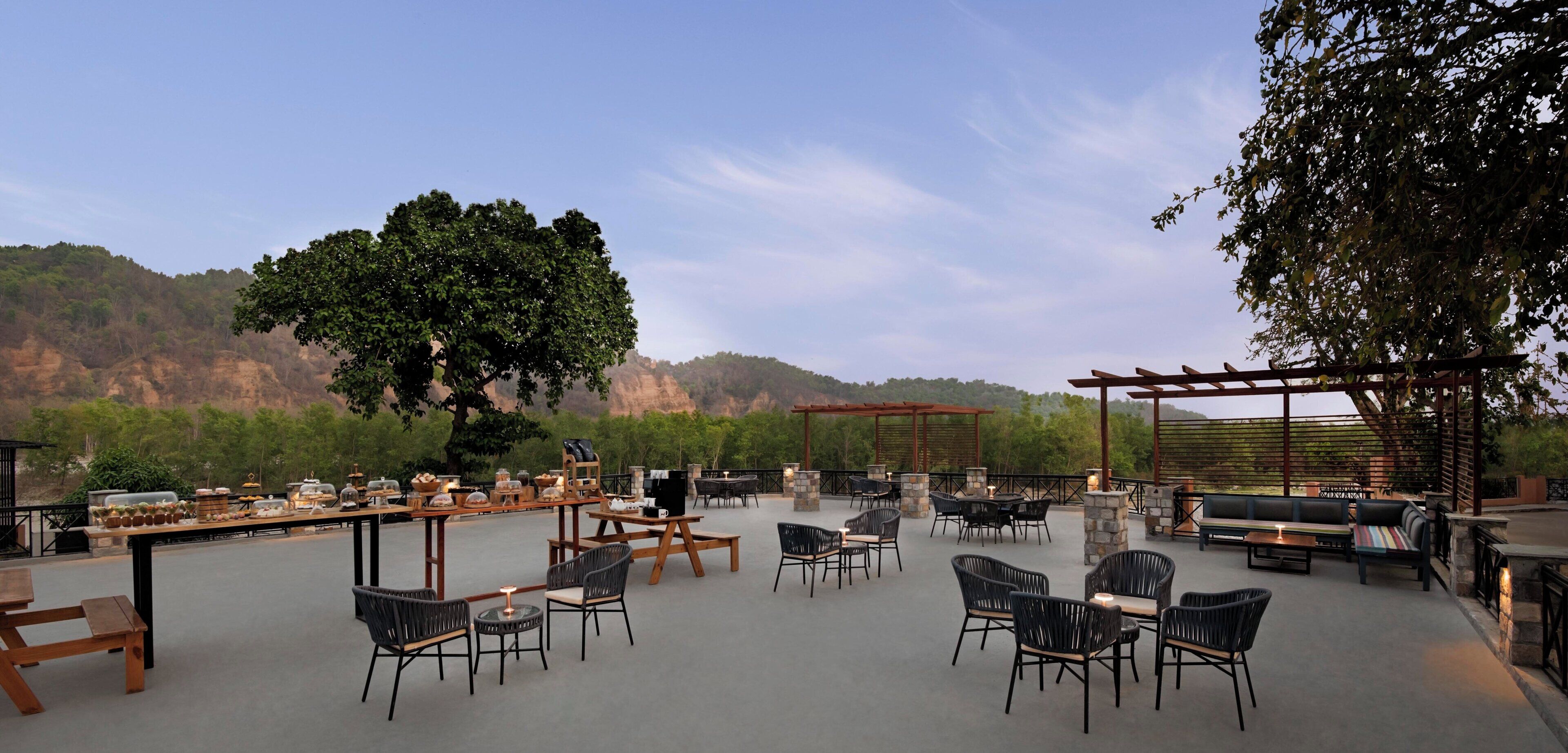 An outdoor patio with tables and chairs, a barbecue grill, and a pergola.