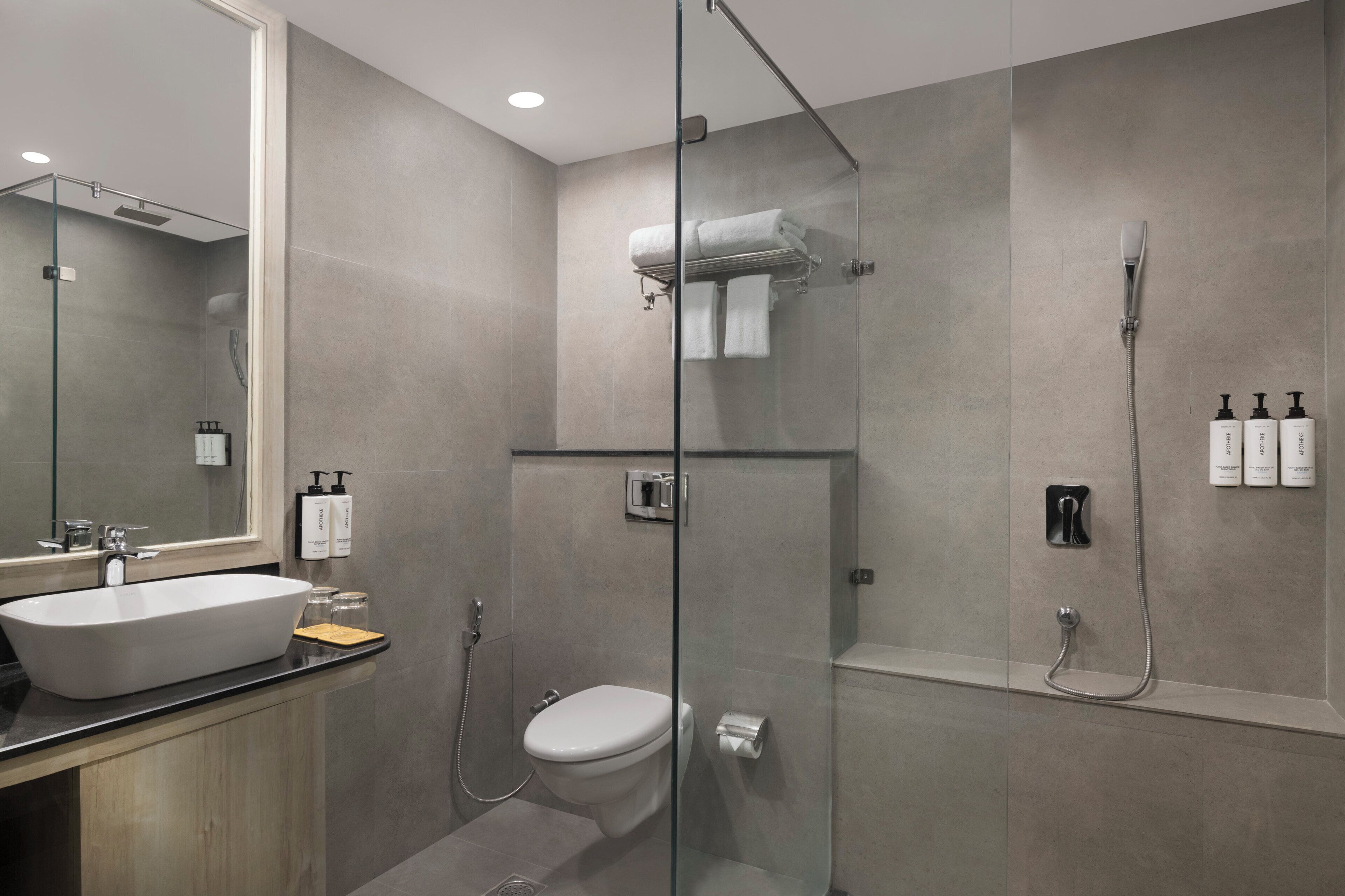 Een moderne badkamer met een douchecabine van glas, een toilet, een wastafel en een spiegel.