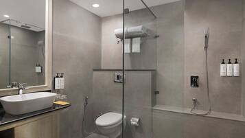 Een moderne badkamer met een douchecabine van glas, een toilet, een wastafel en een spiegel.