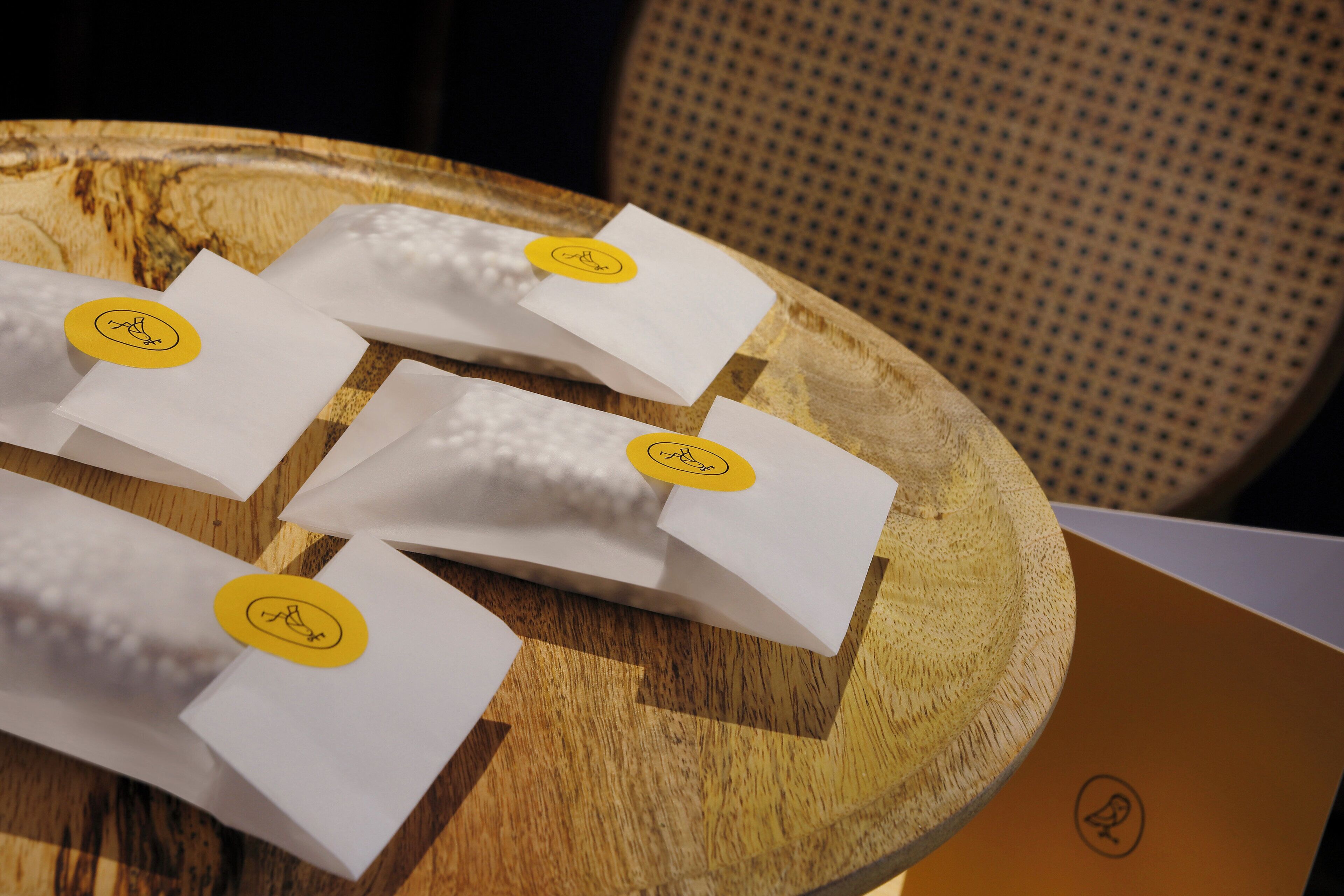 A wooden tray with several white envelopes, each with a yellow sticker.