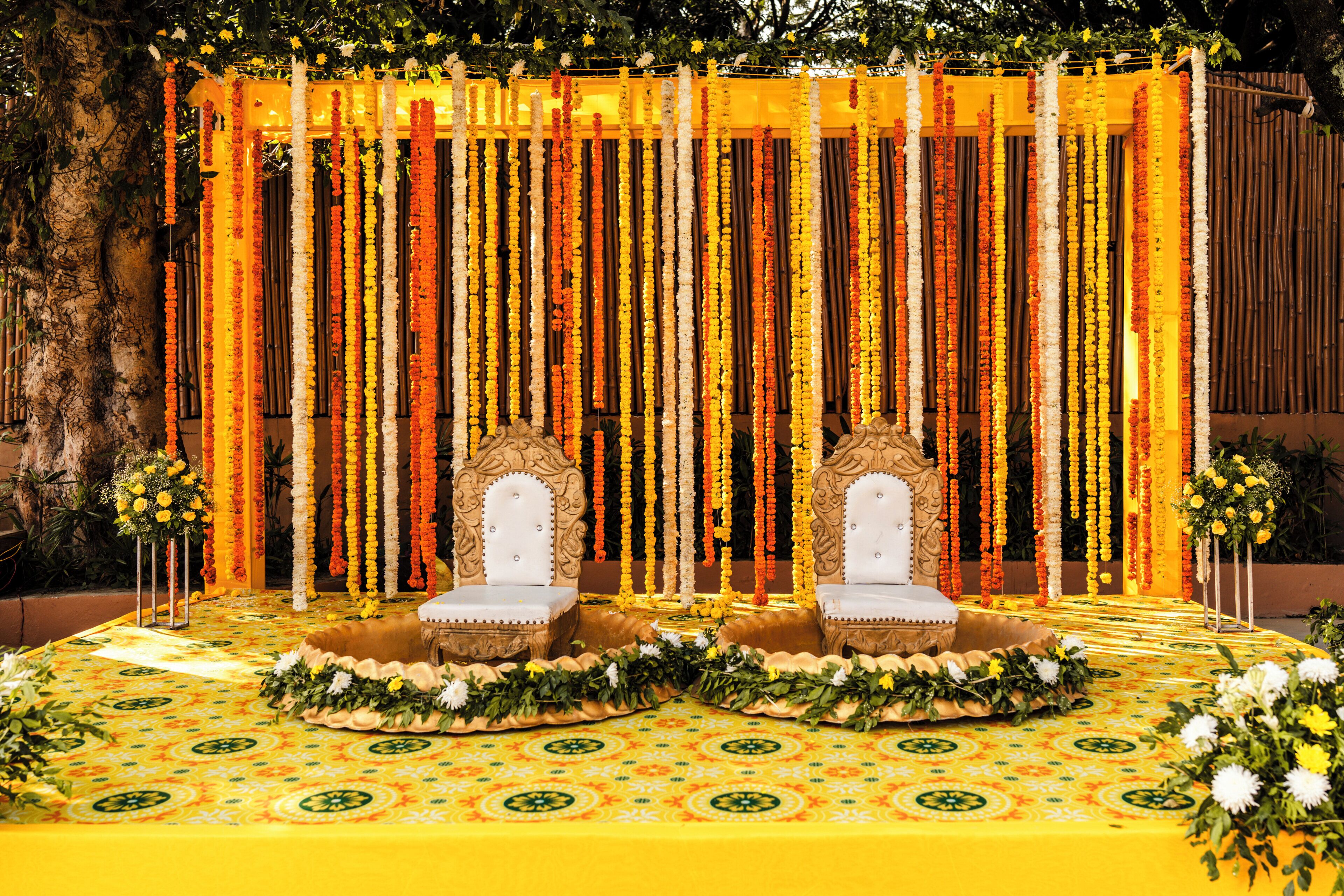 A stage with two ornate chairs, a floral backdrop, and a patterned floor.