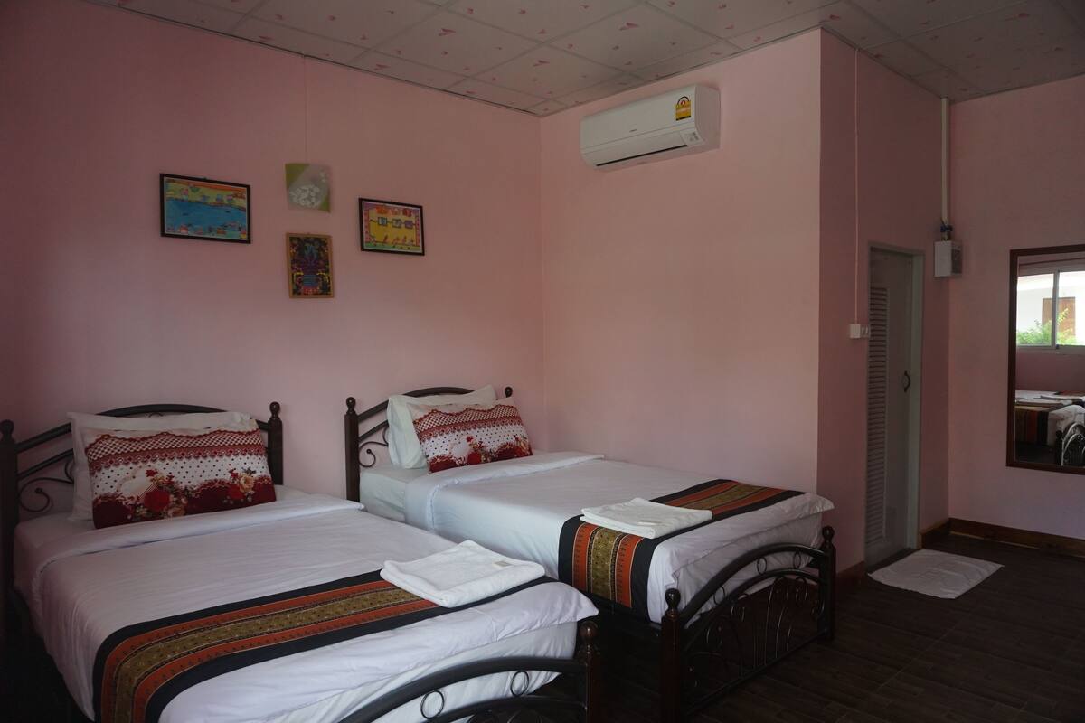 Ein Zimmer mit zwei Betten, rosa Wänden und einer Klimaanlage.