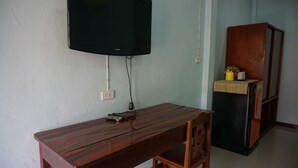 Un tavolo in legno con una televisione montata sopra, una sedia e un piccolo mobile con un vaso di fiori.