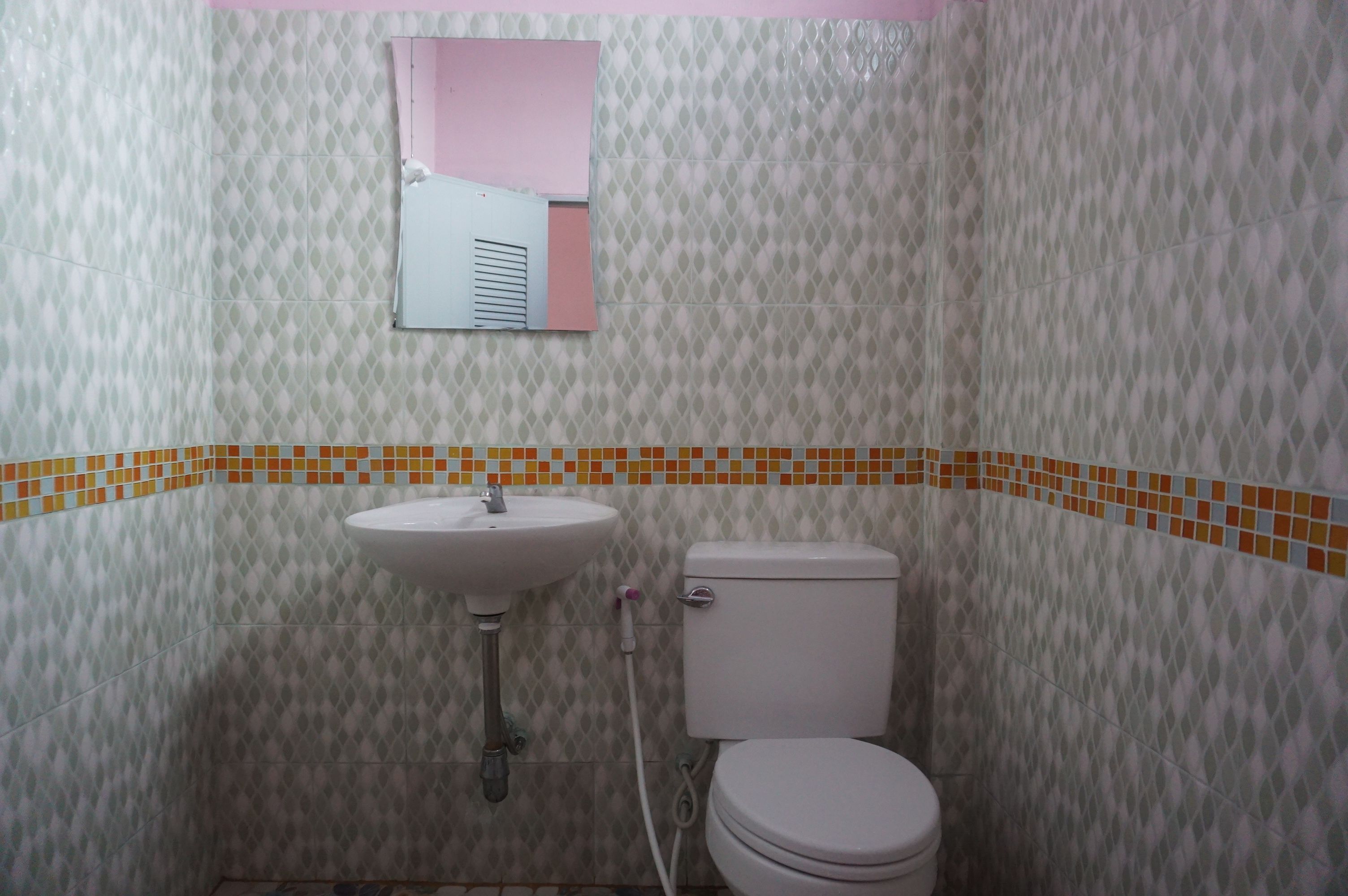 A bathroom with a toilet, sink, and a mirror.