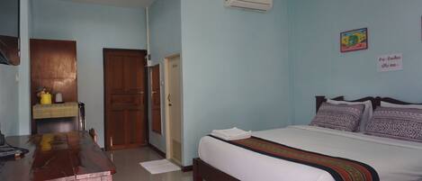 A bedroom with a bed, wooden desk, and a wardrobe.