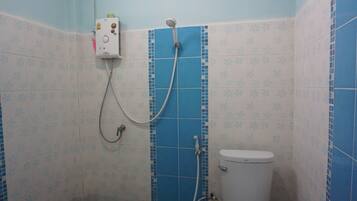 A bathroom with a toilet, a shower with a blue-tiled wall, and a control panel on the wall.