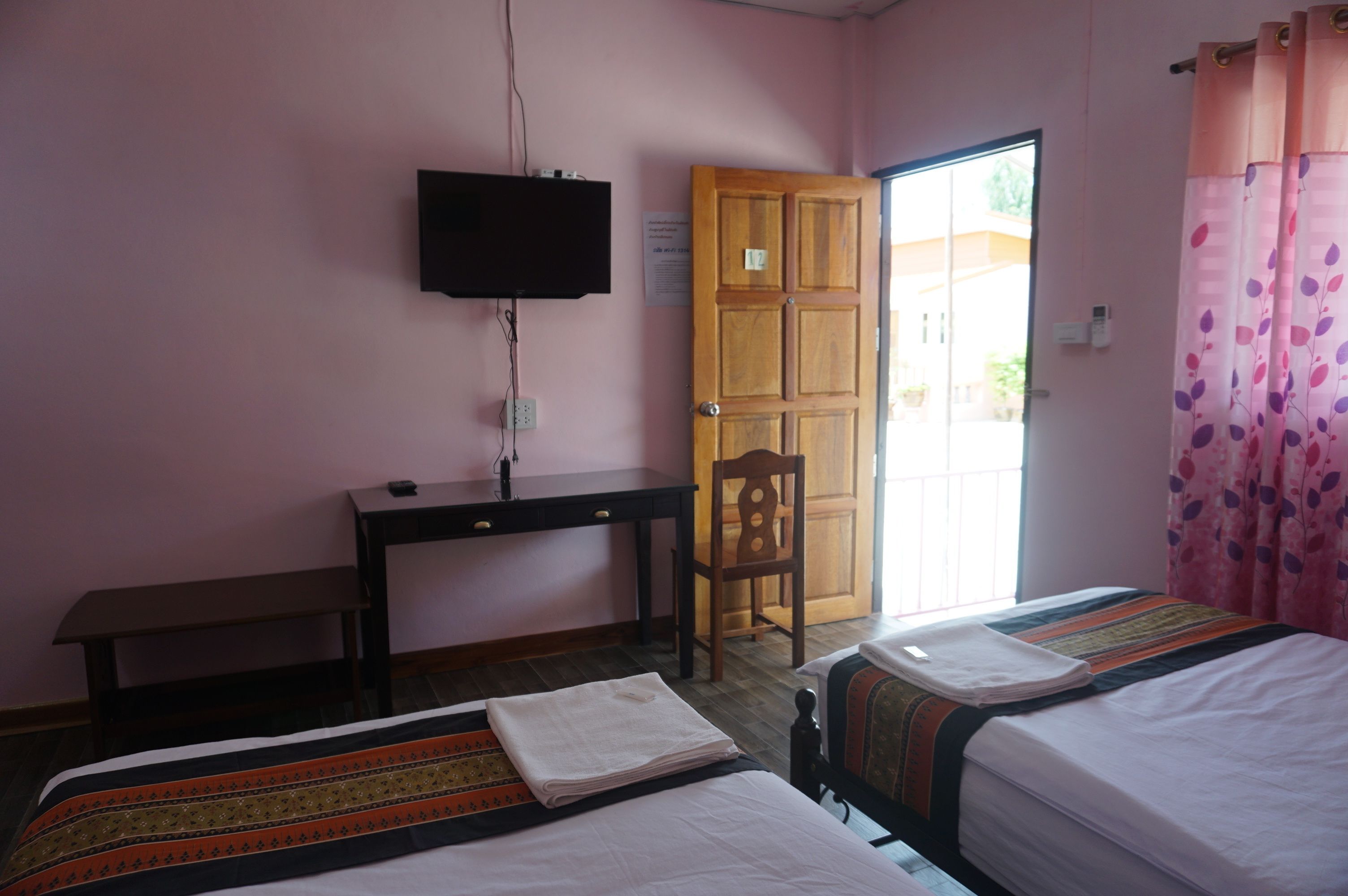 Una habitación con dos camas, un escritorio, una silla, un televisor y una puerta.