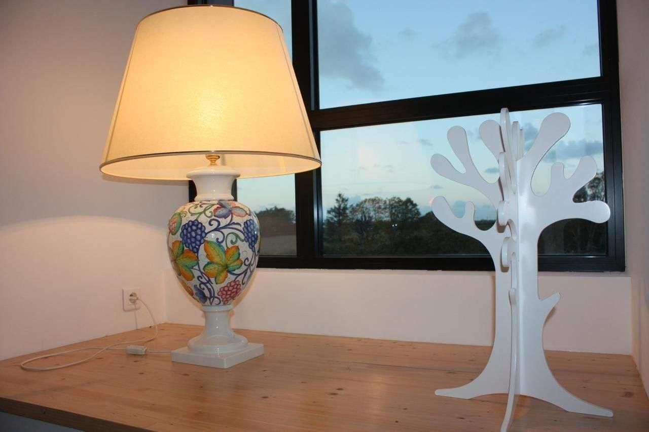 A table with a lamp and a white tree-shaped sculpture.