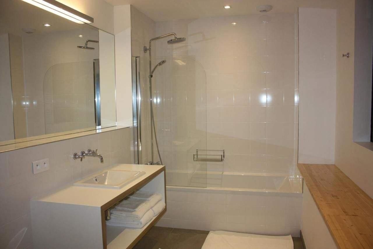 Un baño moderno con ducha envuelta en vidrio, bañera independiente y tocador con espejo.