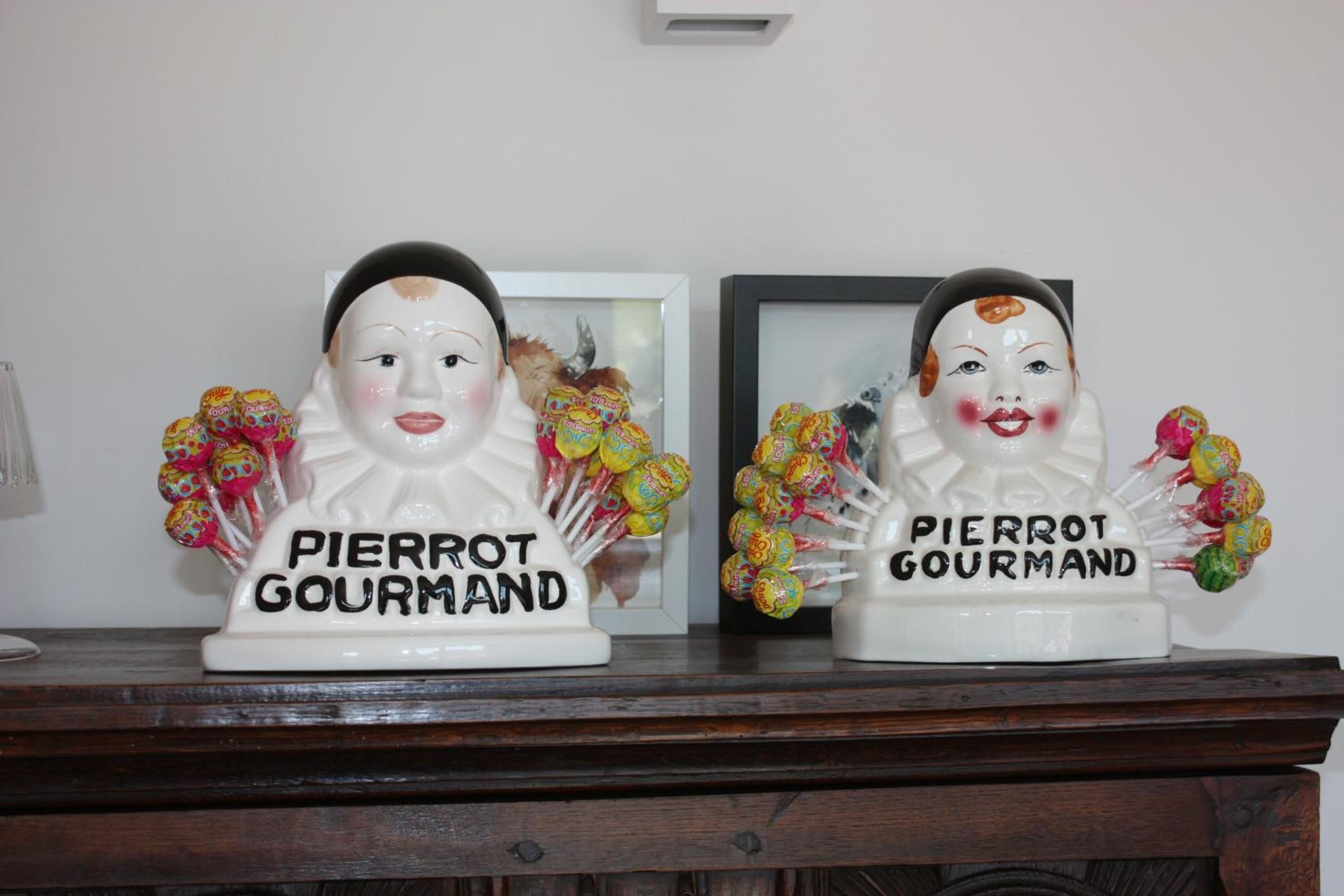 Dos figuritas de cerámica con la etiqueta 'PIERROT GOURMAND' y piruletas de colores.