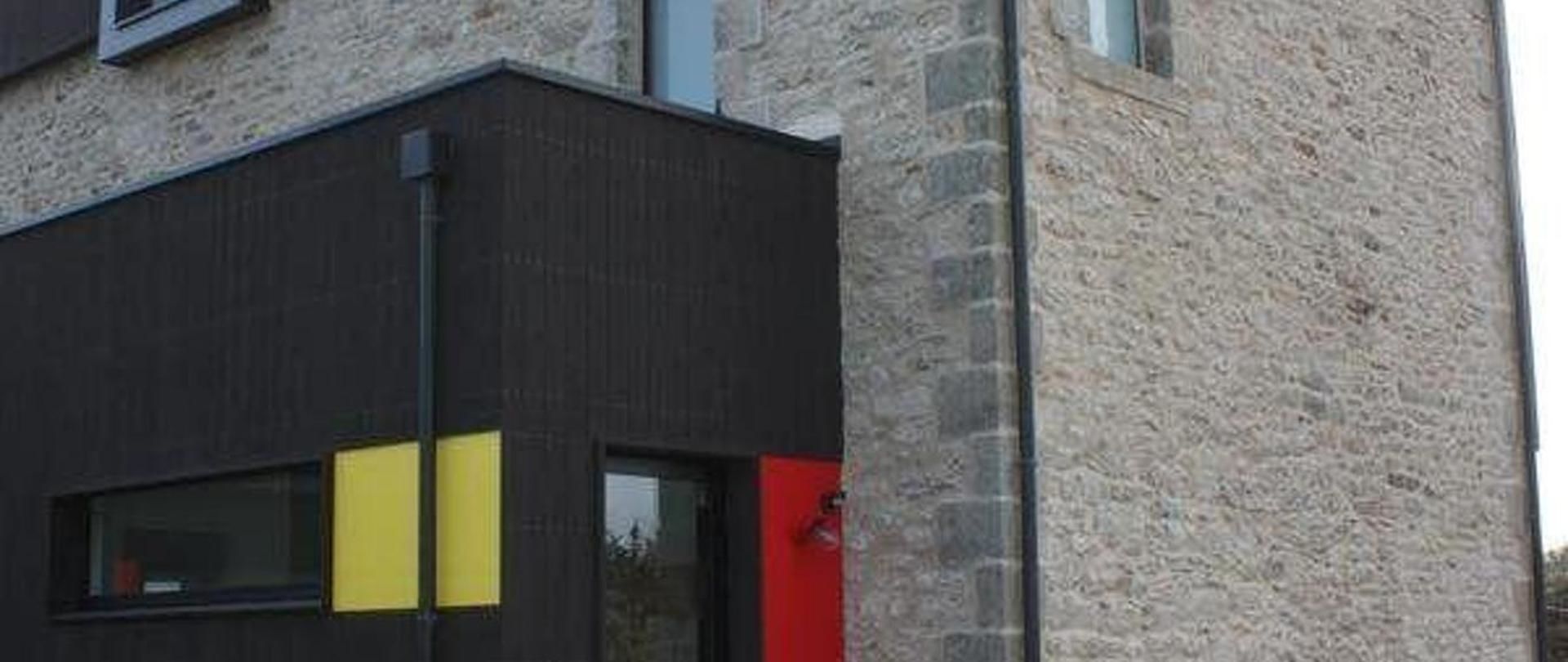 Un edificio con fachada oscura y pared de piedra.