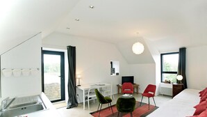 Une chambre d’hôtel moderne équipée d’un lit, d’un bureau, de deux chaises, d’un radiateur et d’une fenêtre.