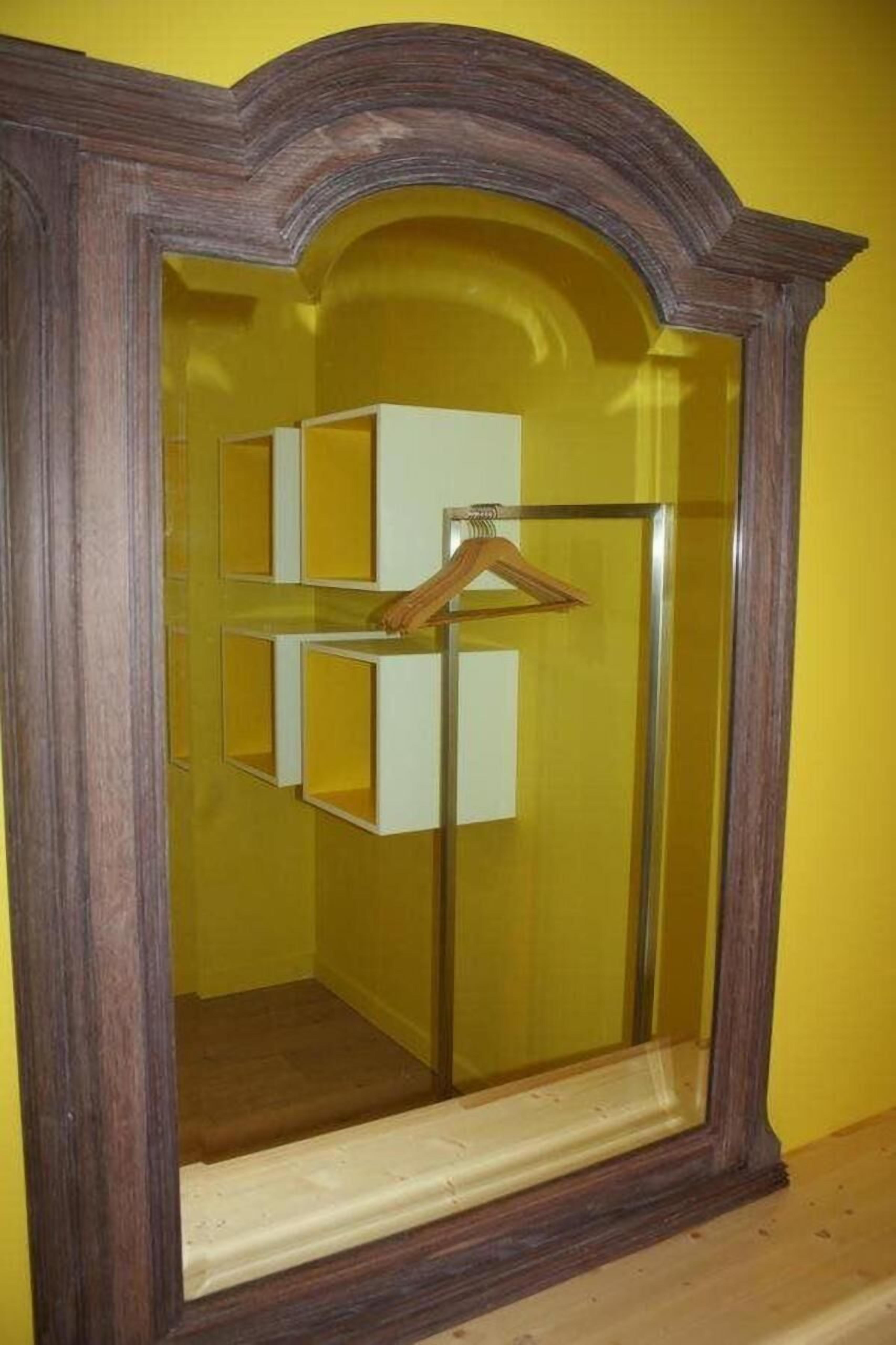 A mirror with a wooden frame and a yellow wall in the background.