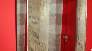 Un miroir avec un cadre qui ressemble à de la pierre, fixé sur un mur rouge.