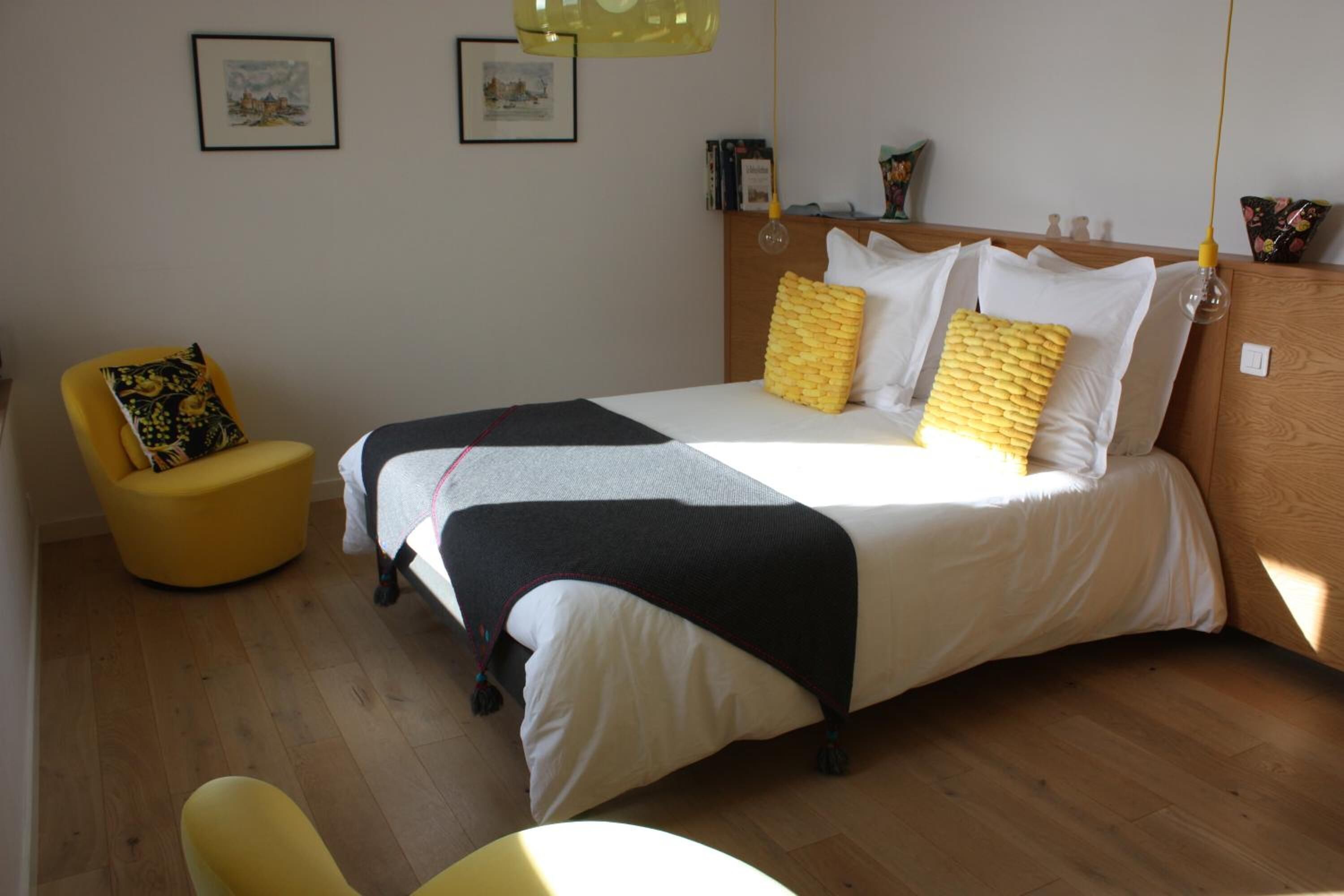 Ein Schlafzimmer mit einem Bett, einem gelben Sessel und einem Holz-Kopfteil.