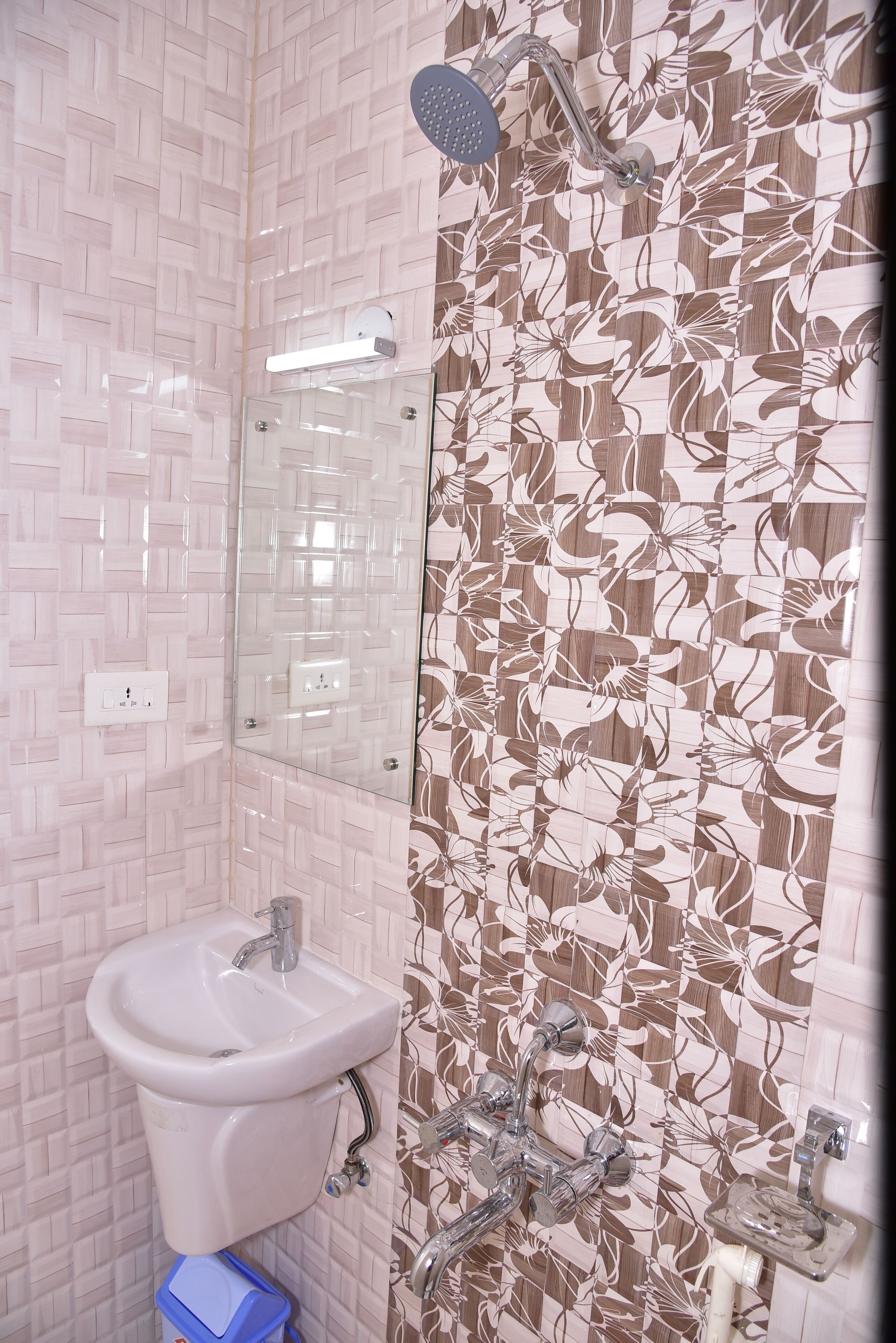 A bathroom with a sink, mirror, shower, and tiled walls.