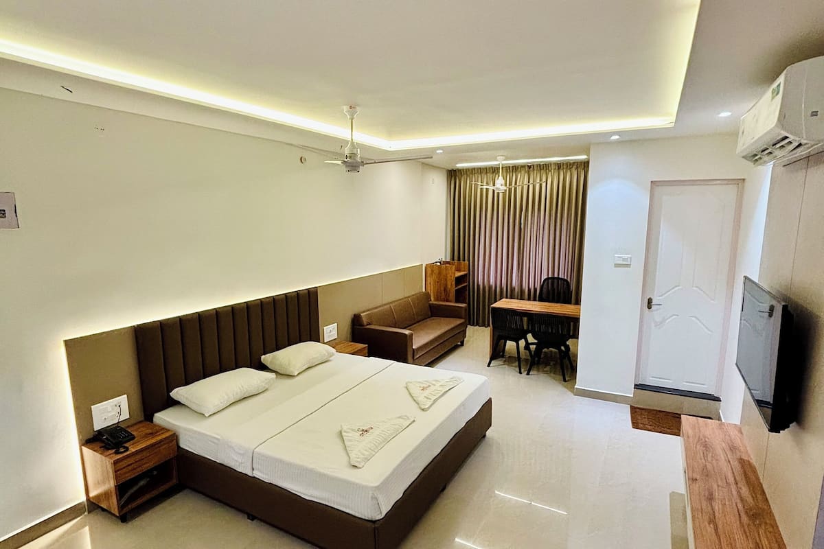 Una habitación de hotel moderna con una cama grande, un escritorio, un sofá y un televisor.