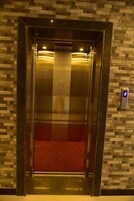 Un ascensor con una pantalla digital que muestra el número 2, una alfombra roja y una pared con un diseño de mosaicos.