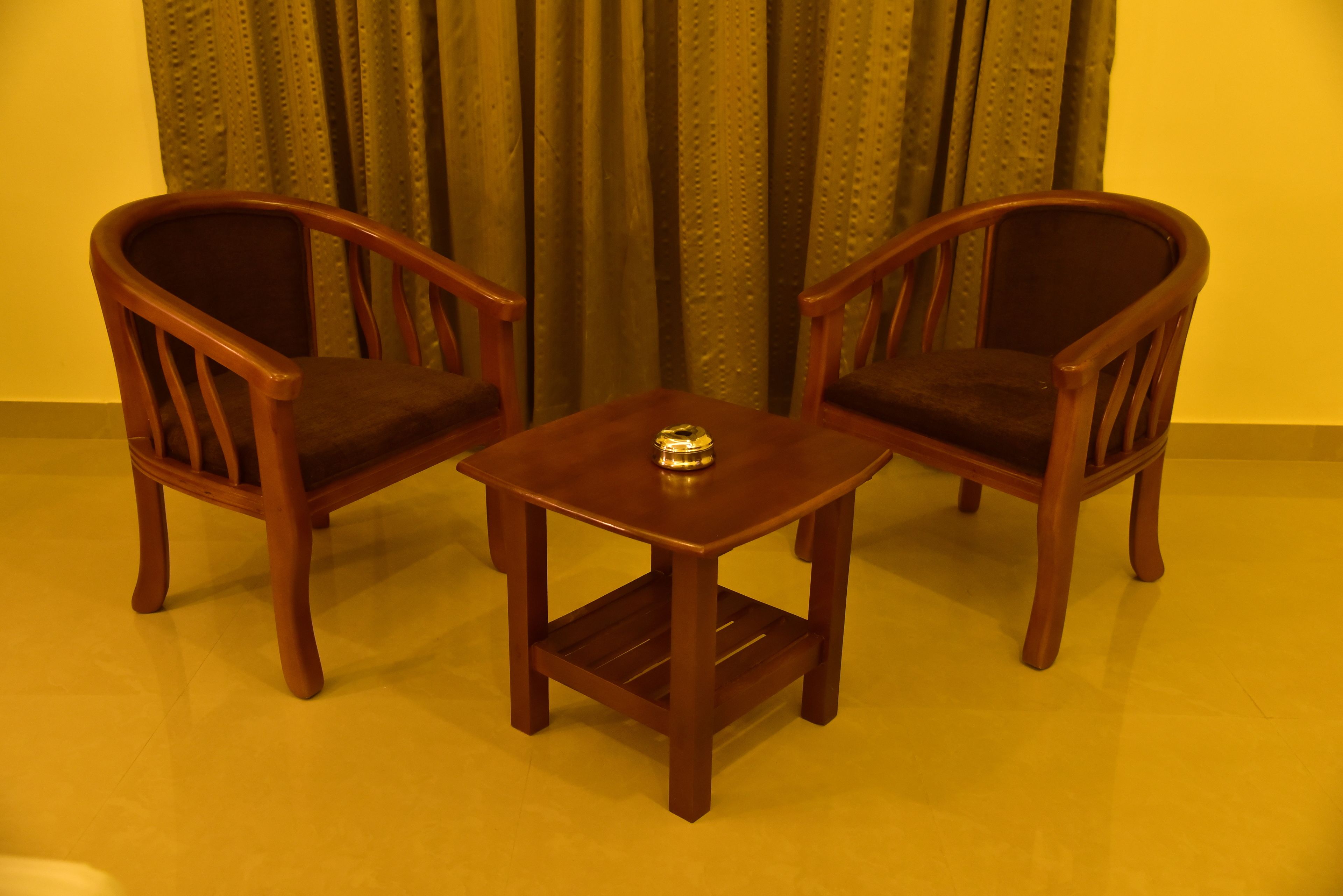 Una pequeña mesa de madera con dos sillas, un estante y un adorno sobre la mesa.