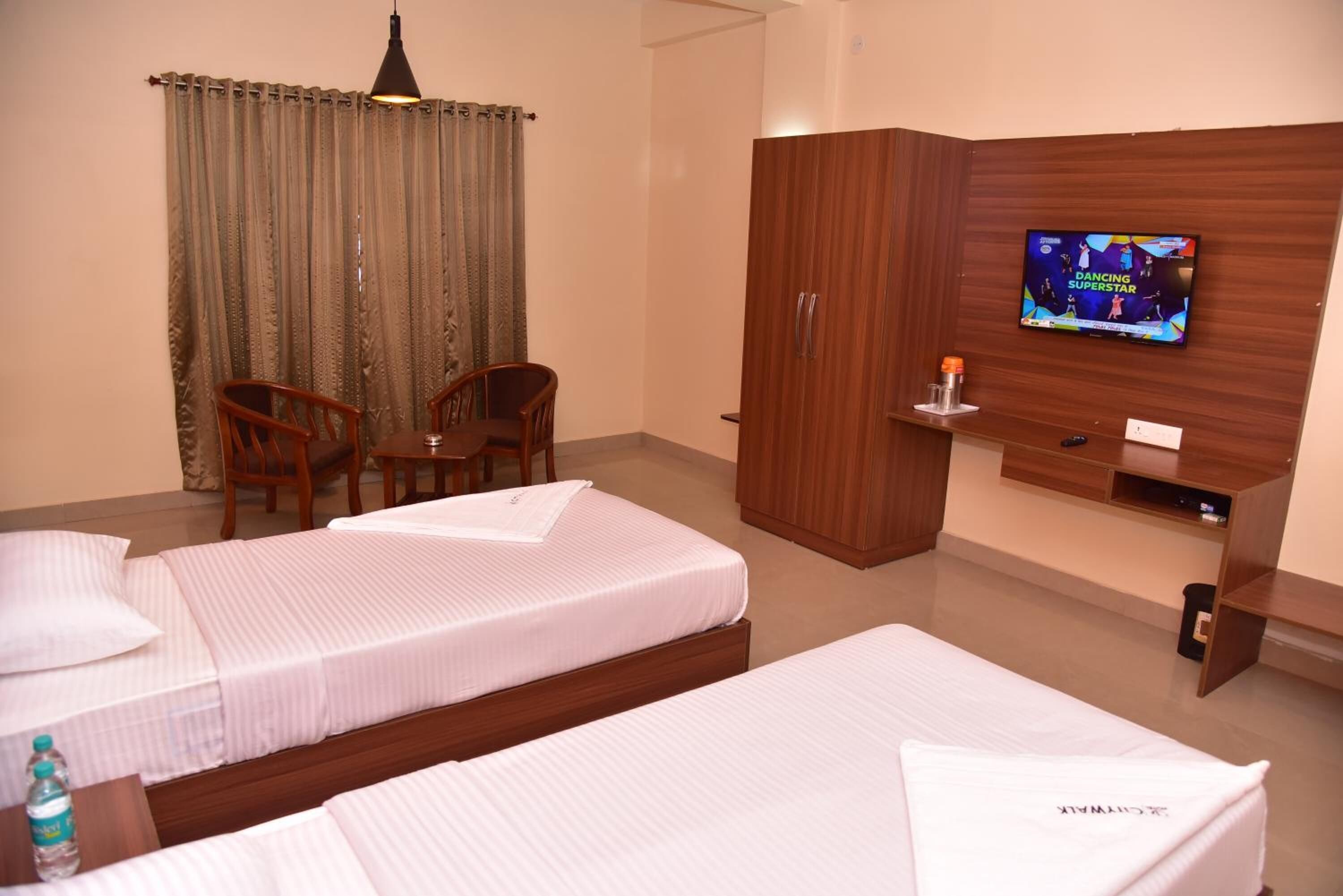 Habitación de hotel con dos camas, televisión, armario y escritorio con silla.