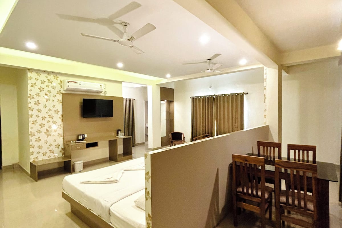 Habitación de hotel con cama, televisión, escritorio y sillas, y ventiladores de techo.