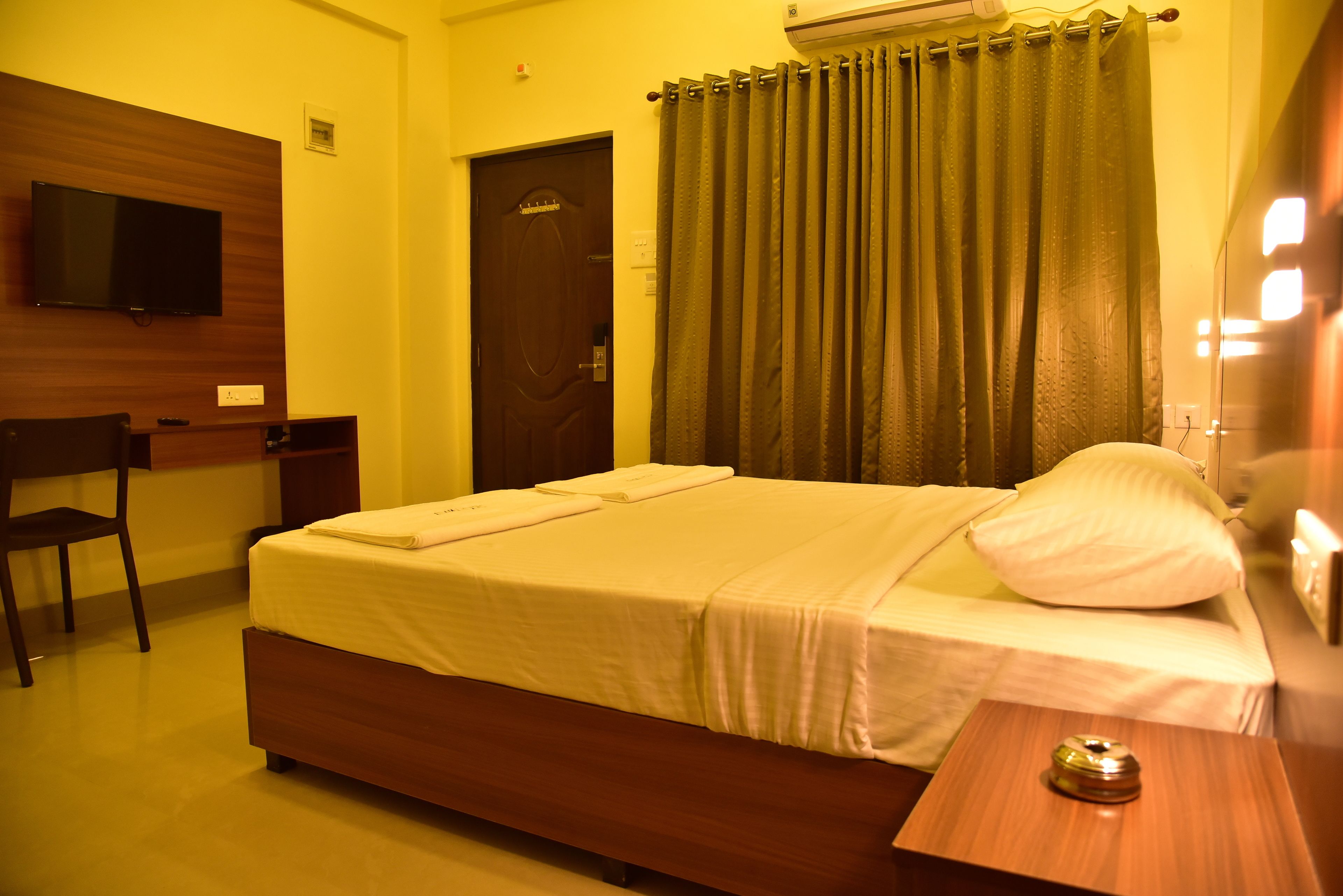A hotel room with a bed, a desk, a chair, a television, and a curtain.