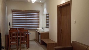 Uma sala de estar moderna com um sofá, uma área de jantar com cadeiras, uma cozinha com pia e um ventilador de teto.
